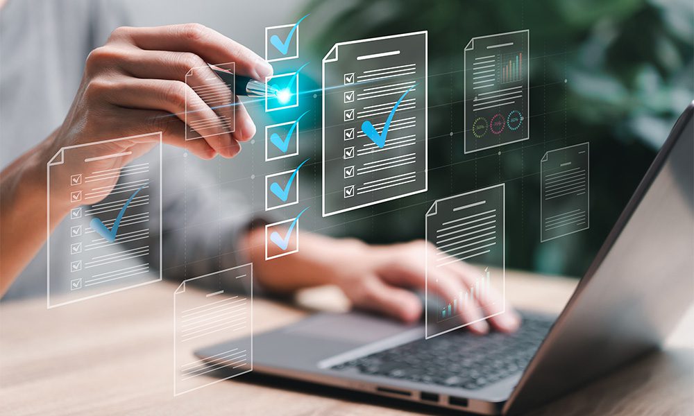 Blog-Closeup-View-of-a-Business-Woman-Sitting-at-her-Desk-Using-a-Laptop-and-Checking-Electronic-Documents-on-a-Virtual-Screen